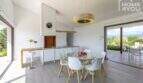 Modern living-dining area of the finca in Sa Pobla with glass round table, white chairs and garden view