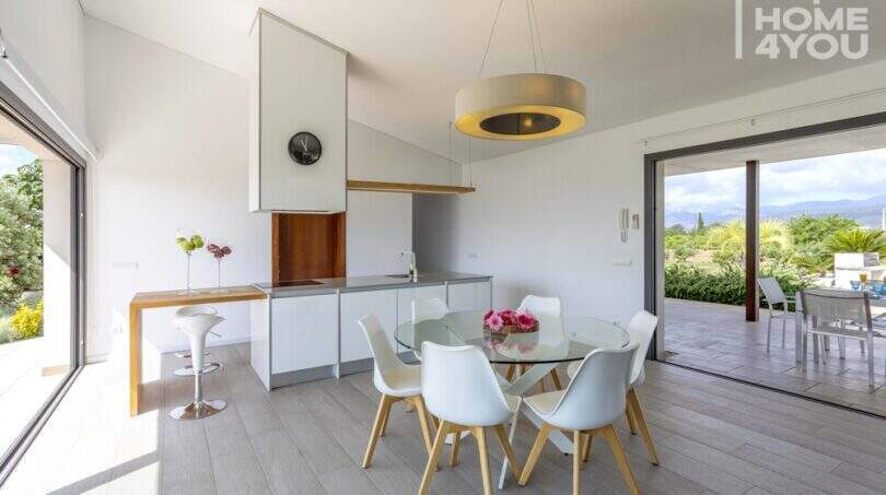 Modern living-dining area of the finca in Sa Pobla with glass round table, white chairs and garden view