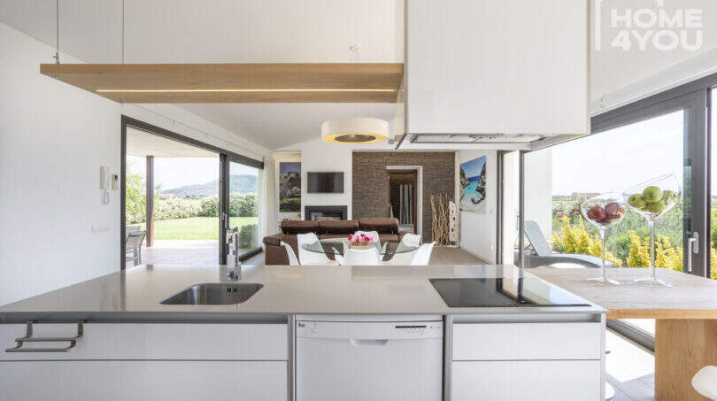Open kitchen with cooking island, view into living room & Mediterranean garden landscape, finca Sa Pobla