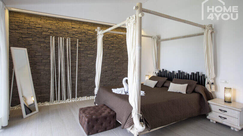 Bedroom of the finca with canopy bed, stone wall and Mediterranean ambience, Sa Pobla