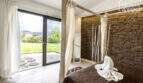 Bedroom with canopy bed, natural stone wall and terrace access to the well-maintained garden of the finca in Sa Pobla