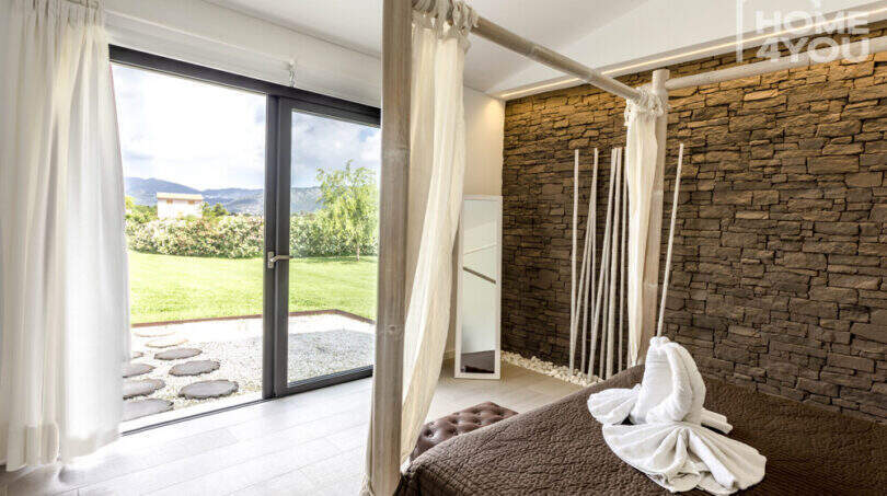Bedroom with canopy bed, natural stone wall and terrace access to the well-maintained garden of the finca in Sa Pobla