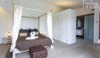 Elegant bedroom of the finca Sa Pobla with canopy bed, bamboo decor and adjoining bathroom.