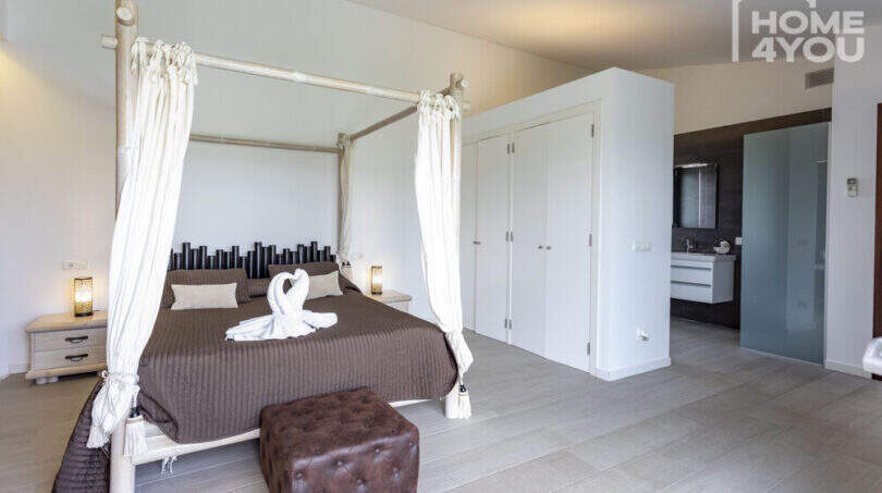 Elegant bedroom of the finca Sa Pobla with canopy bed, bamboo decor and adjoining bathroom.