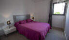 Bedroom of the finca in Sa Pobla with double bed, purple bedding, wooden floor and window with garden view.