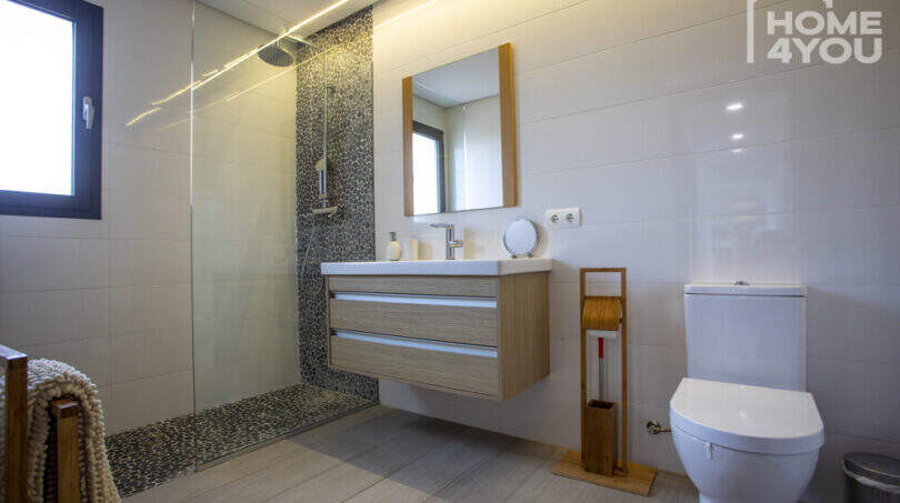 Modern bathroom of the finca in Sa Pobla with walk-in shower, wooden sink and atmospheric lighting.