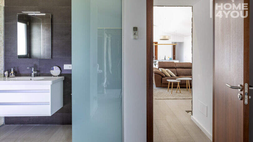 Modern bathroom of the finca in Sa Pobla with sink, mirror and glass partition to living area.
