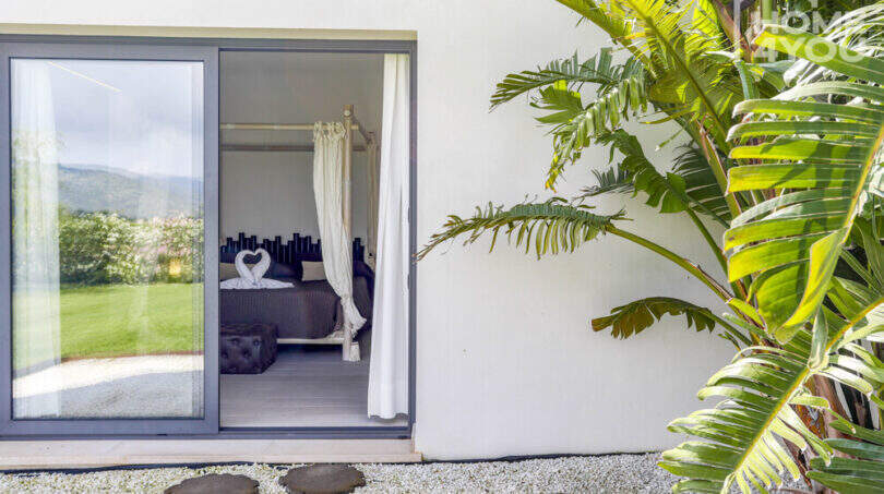 Terrace with tropical plants and view into elegant bedroom with canopy bed, Mediterranean finca Sa Pobla