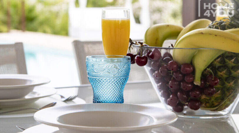 Mediterranean finca Sa Pobla: set dining table with fruit bowl, blue glass and orange juice, pool view