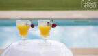 Pool area of the finca in Sa Pobla with two cocktail glasses and cherries at the crystal blue panorama pool