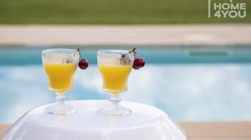 Pool area of the finca in Sa Pobla with two cocktail glasses and cherries at the crystal blue panorama pool