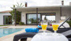 Pool area of the finca in Sa Pobla with loungers, cocktails and modern house in the background
