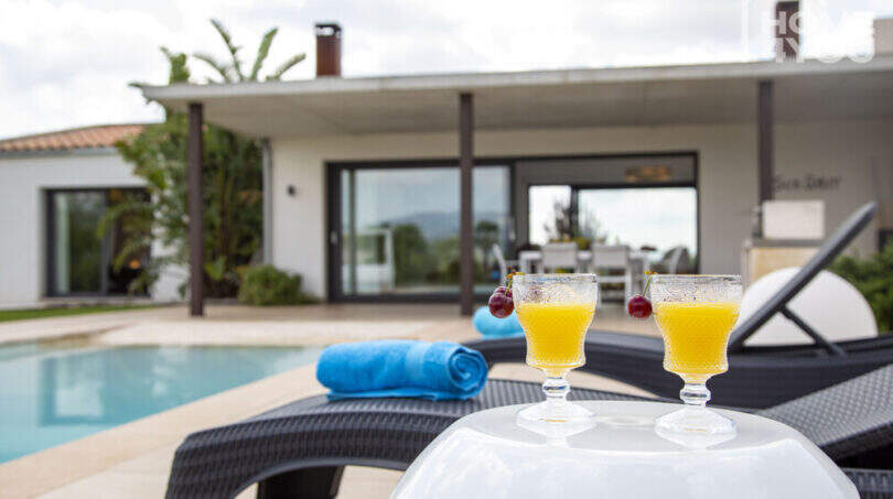 Pool area of the finca in Sa Pobla with loungers, cocktails and modern house in the background