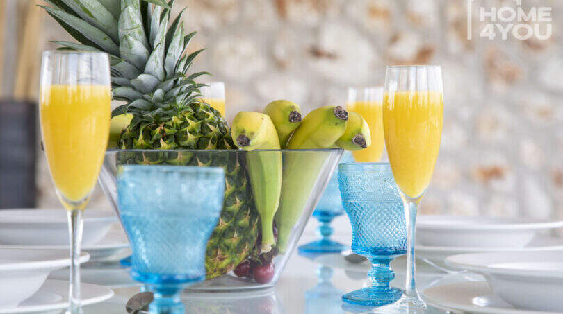 Set dining table of the finca with fruit bowl, blue glasses and fresh juices – Mediterranean ambience.