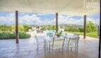 Covered terrace with white dining table, view of pool and mountain panorama of the finca in Sa Pobla