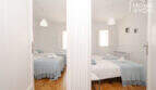 Zwei helle Schlafzimmer mit blauen Tagesdecken, Doppelbetten und weißen Handtüchern im Stadthaus Maria de la Salut