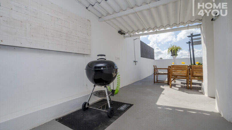 Überdachte Terrasse mit Weber-Kugelgrill und Holzmöbel-Sitzgruppe im Stadthaus Maria de la Salut