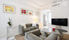 Helles Wohnzimmer mit Ledersofa, Flat-TV, Bogendurchgang und Kunstwerken im mediterranen Stadthaus, Felanitx.
