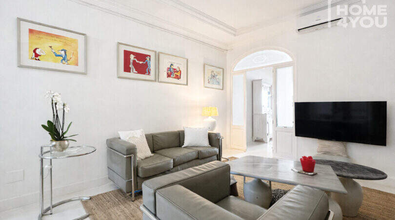 Helles Wohnzimmer mit Ledersofa, Flat-TV, Bogendurchgang und Kunstwerken im mediterranen Stadthaus, Felanitx.