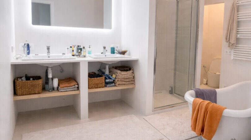 Luxusbad mit freistehender Badewanne, Doppelwaschbecken, beleuchtetem Spiegel und Glasdusche im Ibiza-Stil