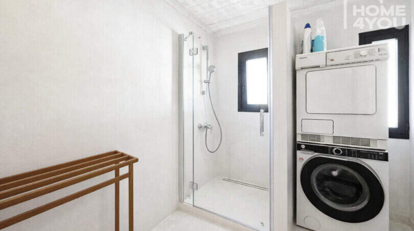 Modernes Badezimmer mit Glasdusche und gestapelter Waschmaschine/Trockner im renovierten Ibiza-Stadthaus
