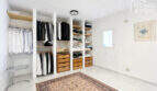 Begehbarer Kleiderschrank mit weißen Regalen, Holzschubladen und Kleiderstangen im modernen Ibiza-Stil-Stadthaus