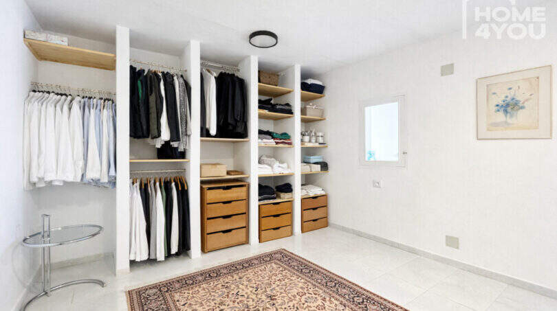 Begehbarer Kleiderschrank mit weißen Regalen, Holzschubladen und Kleiderstangen im modernen Ibiza-Stil-Stadthaus