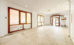 Empty shop premises in Felanitx with tiled floor, wooden frame windows, column and entrance door with arch detail.