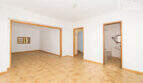 Empty living space with tiled floors, wooden frame doors, bathroom view and passage in the multi-family house Felanitx