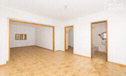 Empty living space with tiled floors, wooden frame doors, bathroom view and passage in the multi-family house Felanitx
