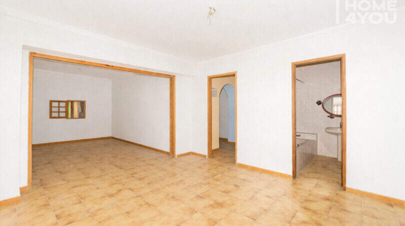 Empty living space with tiled floors, wooden frame doors, bathroom view and passage in the multi-family house Felanitx