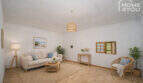 Bright living room with natural materials, rattan armchair, sofa and beach painting in the multi-family house Felanitx