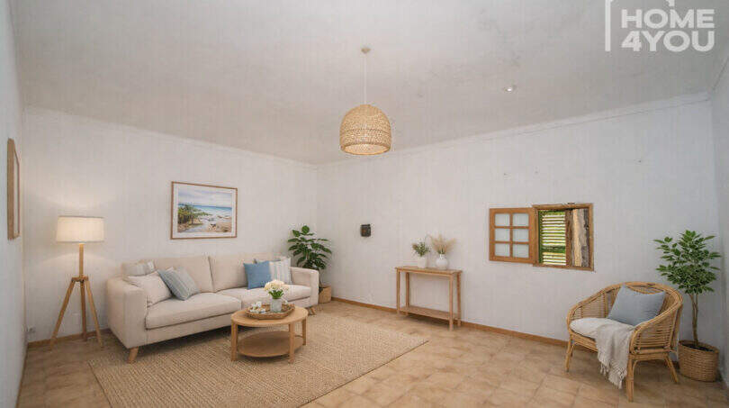 Bright living room with natural materials, rattan armchair, sofa and beach painting in the multi-family house Felanitx