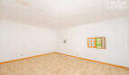 Empty living space with tiled floor, white walls and small wooden window in the multi-family house Felanitx