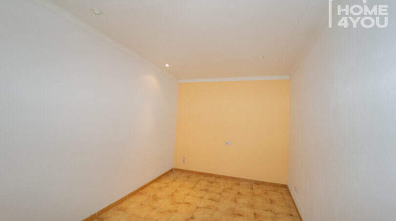 Empty room with light yellow wall accent, parquet floor and recessed lights in the multi-family house Felanitx