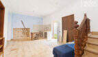 Renovation-needed living space with wooden staircase, tiled floors and blue accent wall in the multi-family house Felanitx
