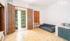 Living room with wooden doors, green shutters, sofa and tiled floor in the multi-family house Felanitx