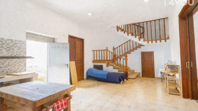 Spacious living area with wooden staircase, tiled floors and natural light in the multi-family house Felanitx