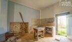 Renovation-needed kitchen with tile backsplash, natural stone wall and access to garden in the multi-family house Felanitx