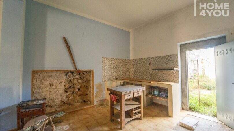 Renovation-needed kitchen with tile backsplash, natural stone wall and access to garden in the multi-family house Felanitx