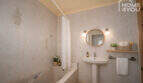 Bright bathroom with bathtub, round mirror, sink and subtle decoration in the multi-family house Felanitx
