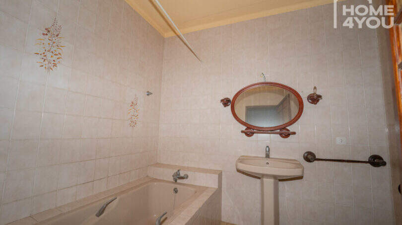 Bathroom with bathtub, sink, oval mirror and floral tile décor in the multi-family house Felanitx