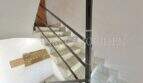 Luminosa escalera con escalones de mármol y barandilla de hierro forjado en apartamento renovado en Palma de Mallorca.