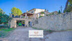 Außenansicht Finca Son Macià mit Natursteinmauer, Garage mit Traktor und überdachter Terrasse im Obergeschoss.