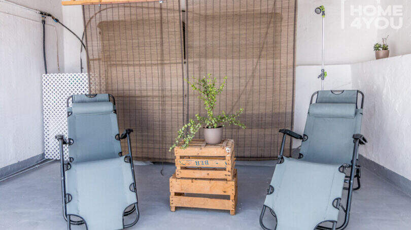 Dachterrasse mit zwei Liegestühlen, Holzkisten-Beistelltisch, Pflanze und Bambus-Sichtschutz im Herrenhaus Porreres.
