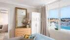 Dormitorio luminoso del apartamento en primera línea de mar en Port Adriano con vistas al mar, cómoda y espejo dorado