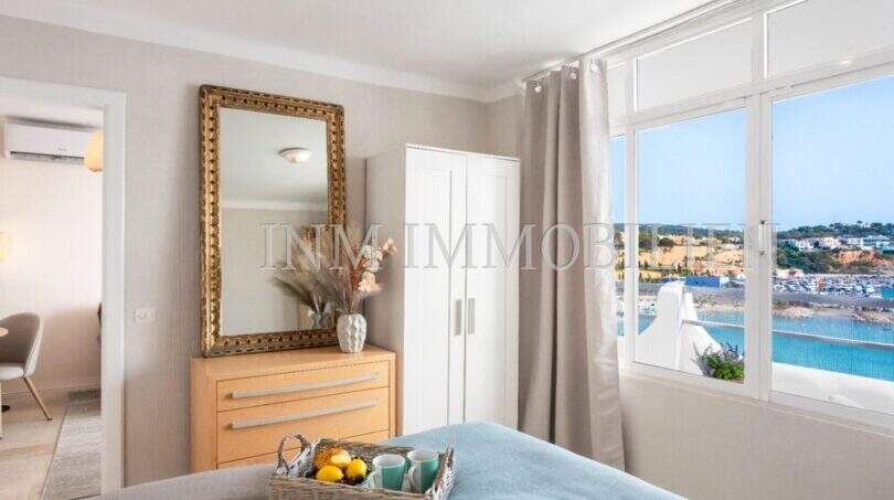 Dormitorio luminoso del apartamento en primera línea de mar en Port Adriano con vistas al mar, cómoda y espejo dorado