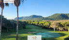Penthouse Canyamel: Panoramablick auf Golfplatz, Pinienwald und Berge unter strahlend blauem Himmel.