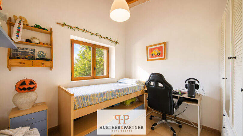 Kinderzimmer der Finca Felanitx mit Hochbett, Schreibtisch, Holzregalen und Fenster zum Grünen