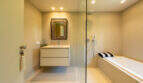 Elegantes Bad mit freistehender Badewanne, Glastrennwand, schwebenden Waschtisch und ornamentalem Spiegel in mallorquinischer Finca.